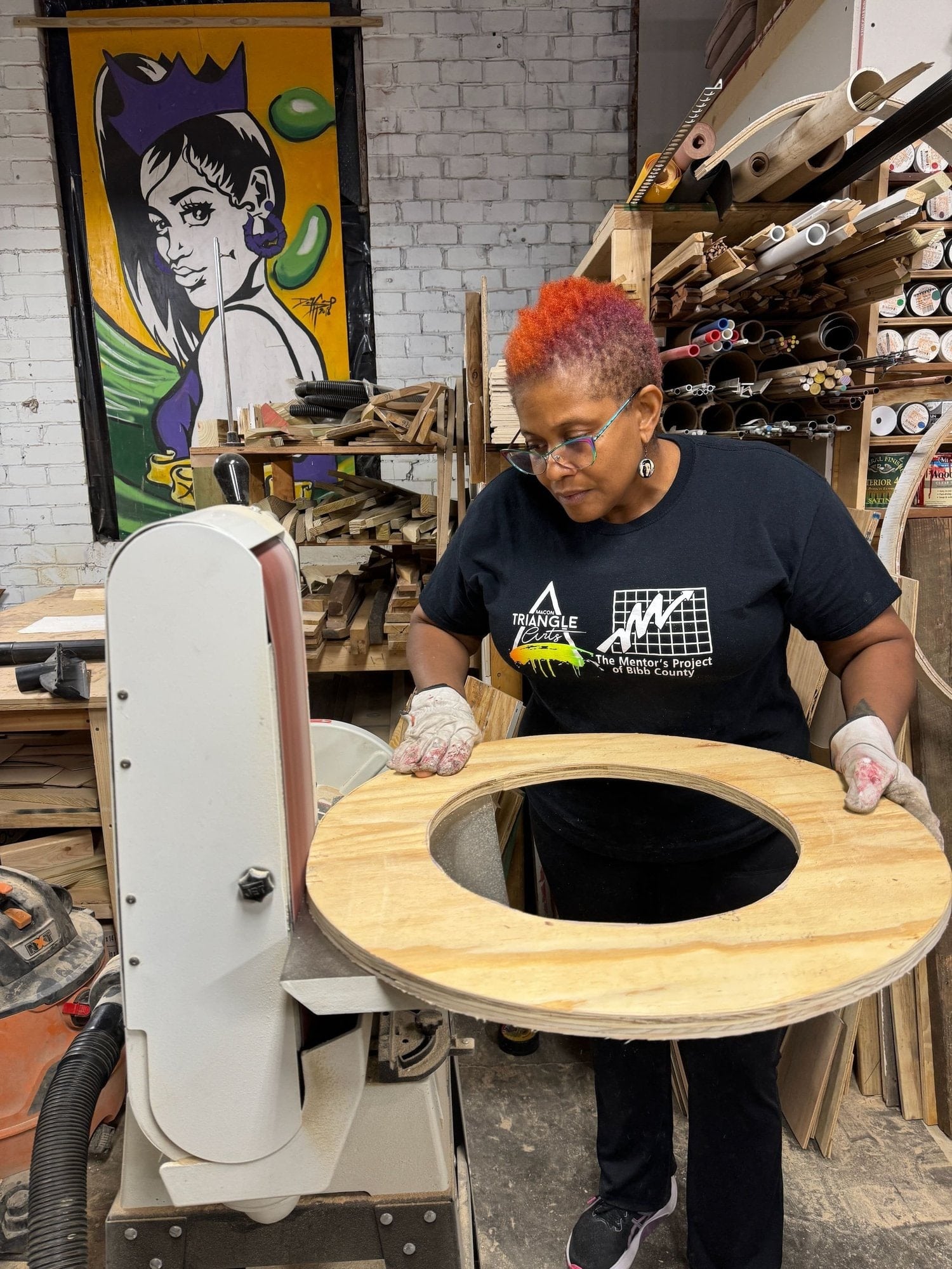 A class participant shaping a circular wooden project in Ric’s studio